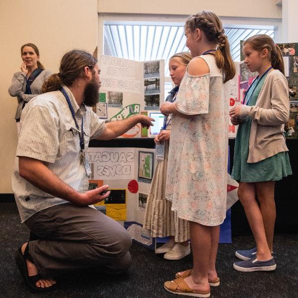 A teacher talks with students about a science project.