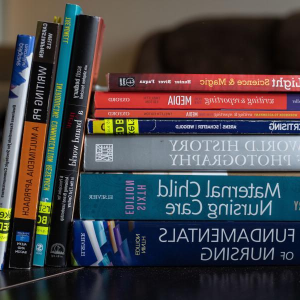 A pile of textbooks on a table, close up.